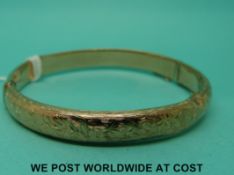 An Edwardian 9ct gold bangle with engraved foliate design (9.