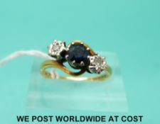An 18ct gold ring set with a round cut sapphire flanked by two diamonds in a twist setting (size M)