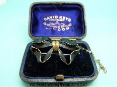 A brooch in the form of a bow decorated with black enamel in original box for David Keys,