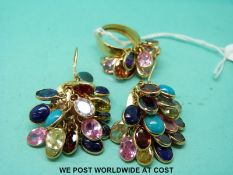 A yellow metal ring set with various gem stones with matching earrings