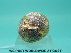 A yellow metal ring set with diamonds in a designer style with textured surface,