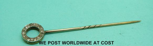 A yellow metal stick pin set with diamonds and sapphires in a circle