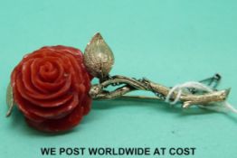 A white metal mounted brooch marked k12 in the form of a rose of carved coral