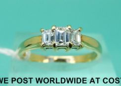 An 18ct gold ring set with three emerald cut diamonds, the centre diamond approximately 0.