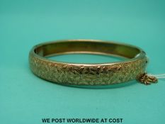A 9ct gold bangle with engraved foliate design (12.