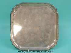 A George V hallmarked silver salver of square form raised on four feet,