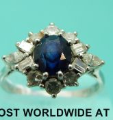 A platinum ring set with a round sapphire surrounded by baguette cut and round cut diamonds (size