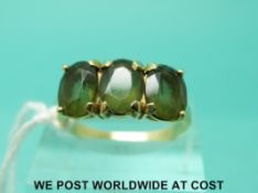 A yellow metal ring marked 14k set with three green garnets (size O)