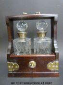An oak two bottle tantalus, cut glass decanters with hallmarked silver collars,