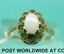 A 9ct gold ring set with an opal surrounded by emeralds (size K)