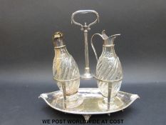 A pair of wrythen moulded cut glass condiment bottles with plated mounts in a boat shaped stand