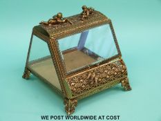 A gilt metal and bevelled glass table top bijouterie cabinet with cherubs to top (W14xD16xH14.