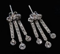 A pair of platinum earrings in the form of bows with three drop sections,