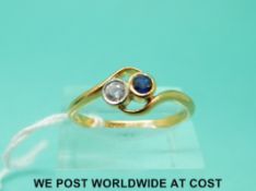 A 22ct gold ring set with a diamond and a sapphire in a twist setting (size U)