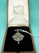 A platinum and 9ct gold brooch set with diamonds and two pearls on a circular frosted mount,