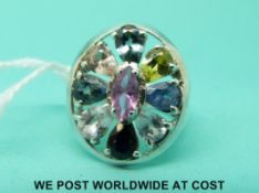 A silver ring set with multi-coloured sapphires with a marquise pink sapphire to the centre