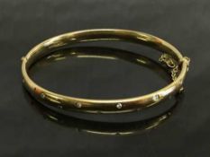 A 9ct gold shaped bangle set with diamonds, diameter 6.3 cm x 5.5 cm, 25g.
