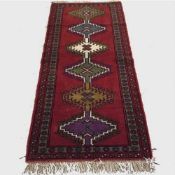 A wool Eastern carpet runner on red ground, 191 cm x 85 cm.