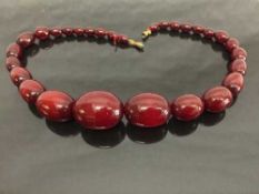An early twentieth century cherry amber necklace, 64.9g.