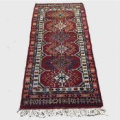 A wool Eastern carpet runner on red ground, 188 cm x 87 cm.