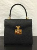 Gucci : A lady's hand bag, black leather, with brass fittings, with single fixed carry handle,