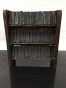 A late nineteenth/early twentieth century miniature oak bookshelf, holding 39 miniature novels,