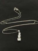 A graduated three stone diamond pendant set in platinum, suspended upon an 18ct white gold chain.