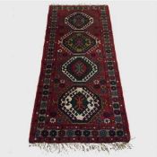 A wool Eastern carpet runner on red geometric ground, 186 cm x 84 cm.