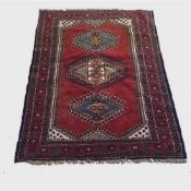 A wool Eastern carpet on red ground medallion central panel, 172 cm x 124 cm.