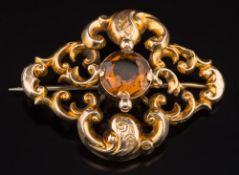 A Victorian gold and citrine mounted single stone brooch: of scroll work design with central,
