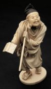 A Japanese okimono of a scholar: dressed in traditional costume holding an open book in his right