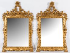 A pair of carved giltwood wall mirrors:, with pierced flowerhead, foliate and scroll crestings,