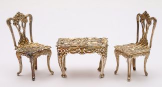 A collection of silver miniature tables and chairs,