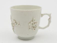 An early Bow 'blanc-de-chine' coffee cup: with scroll handle and applied with sprays of prunus
