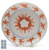 A Chinese saucer dish: painted in iron-red with five bats within a border of twelve further bats