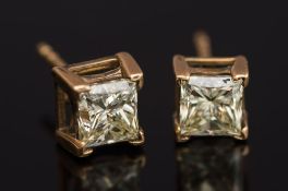 A pair of princess-cut diamond single stone ear studs: each set with a single princess-cut diamond