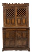 An early 18th Century Continental oak food cupboard:, the upper part with a castellated pediment,