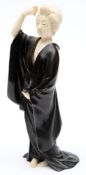 A Japanese bronze and ivory okimono: of a courtesan combing her hair and dressed in loose robes,