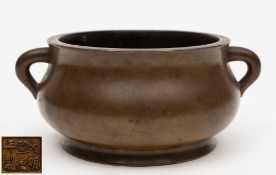 A Chinese bronze censer: of compressed plain circular form, with loop carrying handles to the sides,