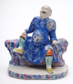 A Chinese famille rose porcelain figure: of a seated laughing man leaning back,