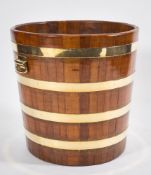 A 19th Century teak and brass bound peat barrel:, with brass carrying handles to the sides,