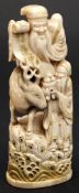 A Japanese carved and stained ivory okimono of Jurojin: the smiling god seated on a deer and
