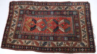 A Kazak rug:, the brick red field with four serrated diagonal geometric medallions,