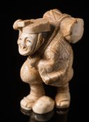A Japanese carved ivory okimono: Meiji period (1864-1912) of a travelling musician with a drum on