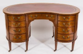 An Edwardian mahogany and inlaid kneehole desk:, of kidney-shaped outline, banded in satinwood,