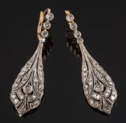 A pair of diamond mounted pendant drop earrings: each with a pierced tear-drop millegrain-set with