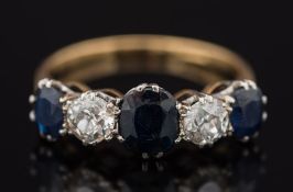 A gold, sapphire and diamond five stone ring: with graduated, oval sapphires between round,