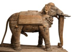 A large stripped wood Indian elephant: dressed in ceremonial hangings, with drapes and bosses,
