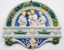 An Italian 'Della Robbia' maiolica plaque: of arched form,