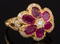 A modern ruby and diamond flower head cluster ring: with six petals each inset with an oval ruby,